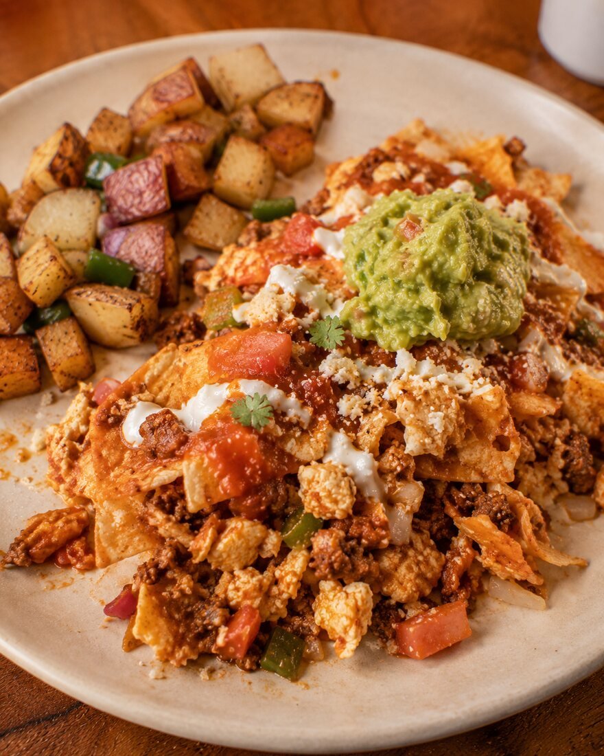 Chilaquiles topped with salsa, cheese, sour cream and guacamole